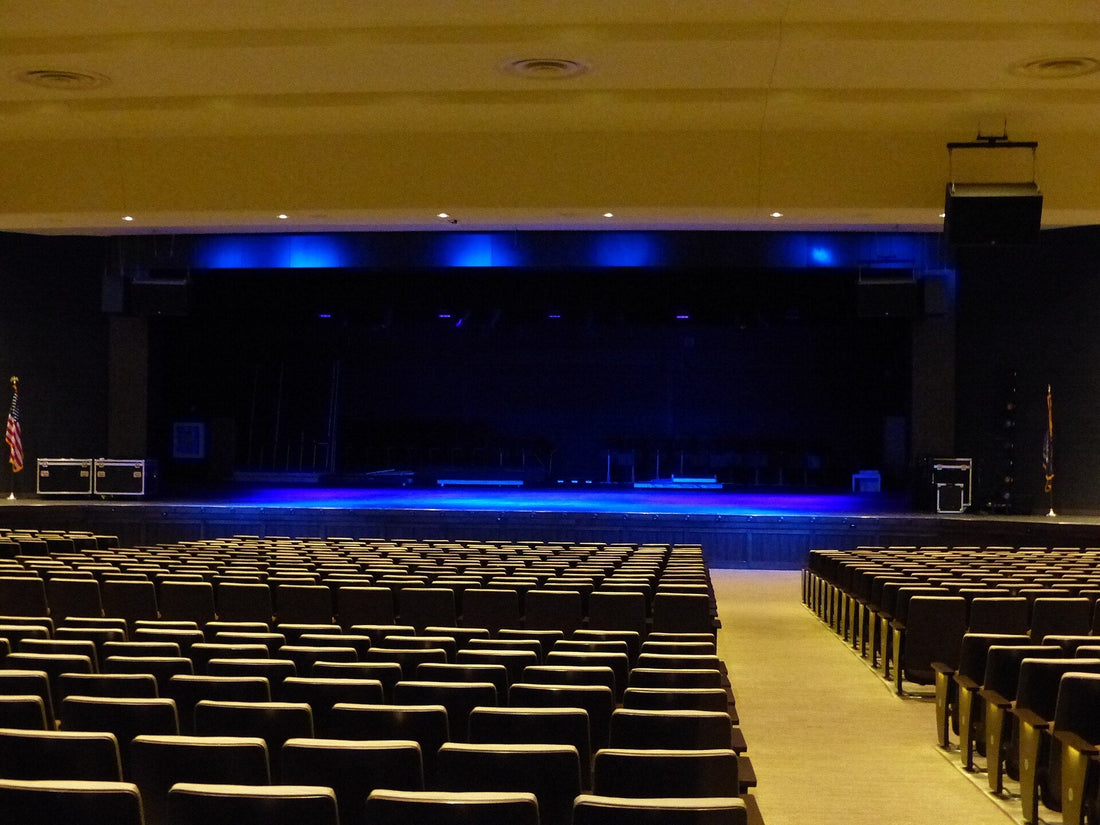 Empty high school auditorium with a blue-lit stage, for a Bixby fine arts story