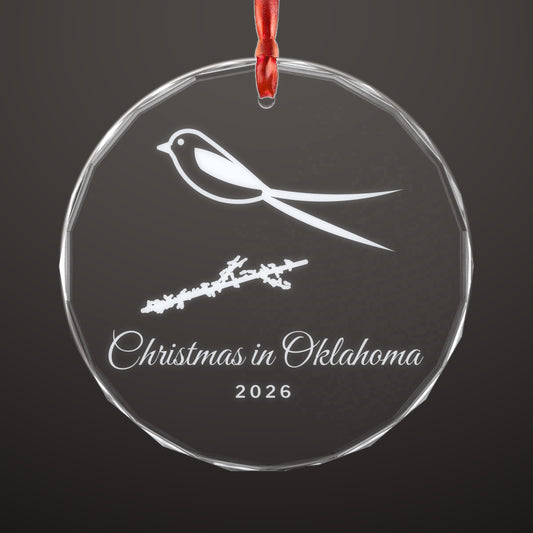 Clear round crystal ornament engraved with a scissortail flycatcher on a branch and the words Christmas in Oklahoma 2026, hung on a red ribbon