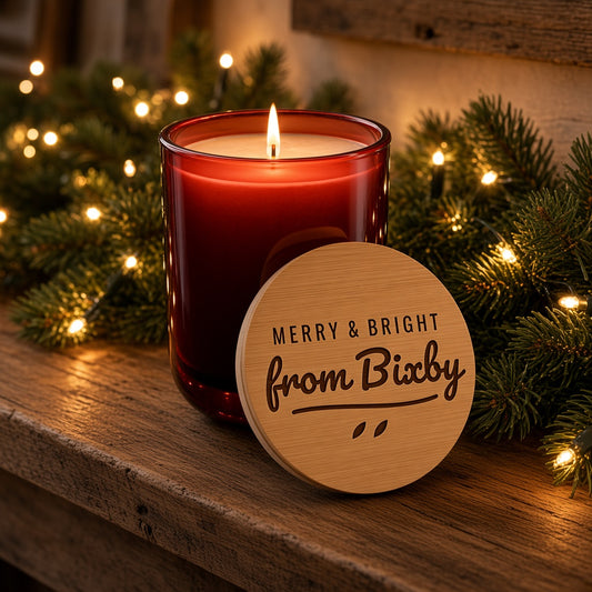 Lit cranberry soy candle on a Christmas mantel with engraved Merry & Bright from Bixby lid